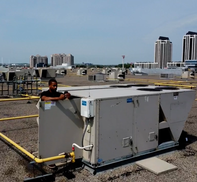 Man with phone on rooftop HVAC
